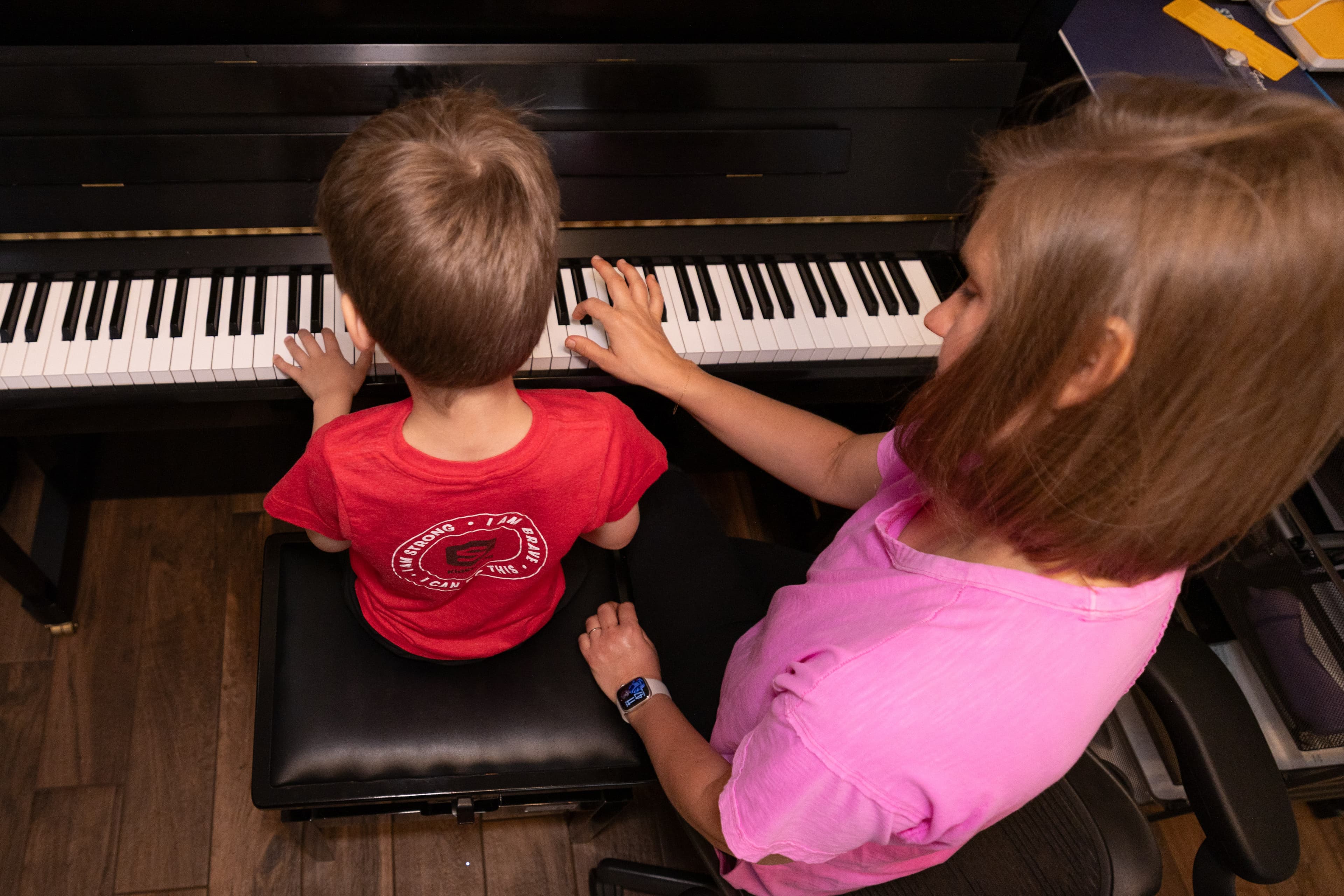 Instructor guiding a child's hands at the piano